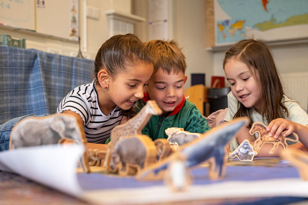 Three children absorbed in hands-on classroom material